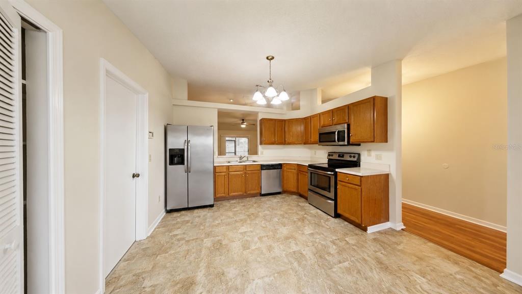 A kitchen features wood cabinets, stainless steel appliances, and light-colored tile flooring — 127 TITAN DRIVE, DAVENPORT, FL