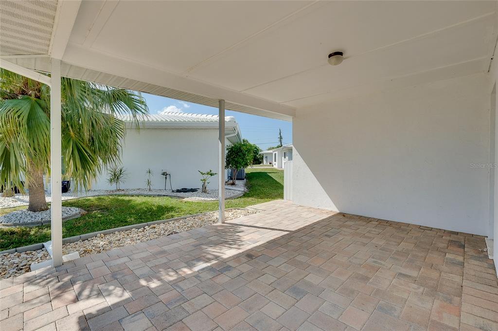 A covered patio features light-colored pavers and a white ceiling with a single light fixture — 446 CIRCLEWOOD DRIVE UNIT L2, VENICE, FL