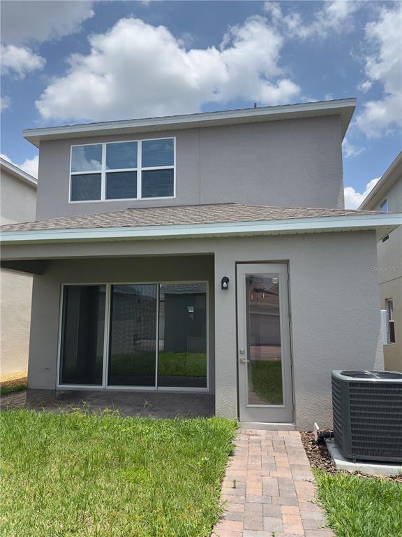 The rear exterior of a two-story gray house features a patio and a glass door — 12560 WESTHAVEN OAK DRIVE, WINTER GARDEN, FL