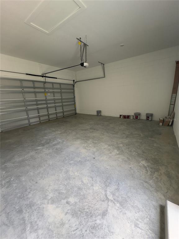 An empty garage features a concrete floor, white block walls, and a metal sectional door — 12560 WESTHAVEN OAK DRIVE, WINTER GARDEN, FL