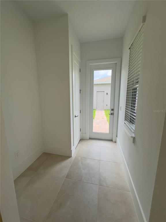 A tiled hallway features a white door, a window with blinds, and a glass-paneled exterior door — 12560 WESTHAVEN OAK DRIVE, WINTER GARDEN, FL