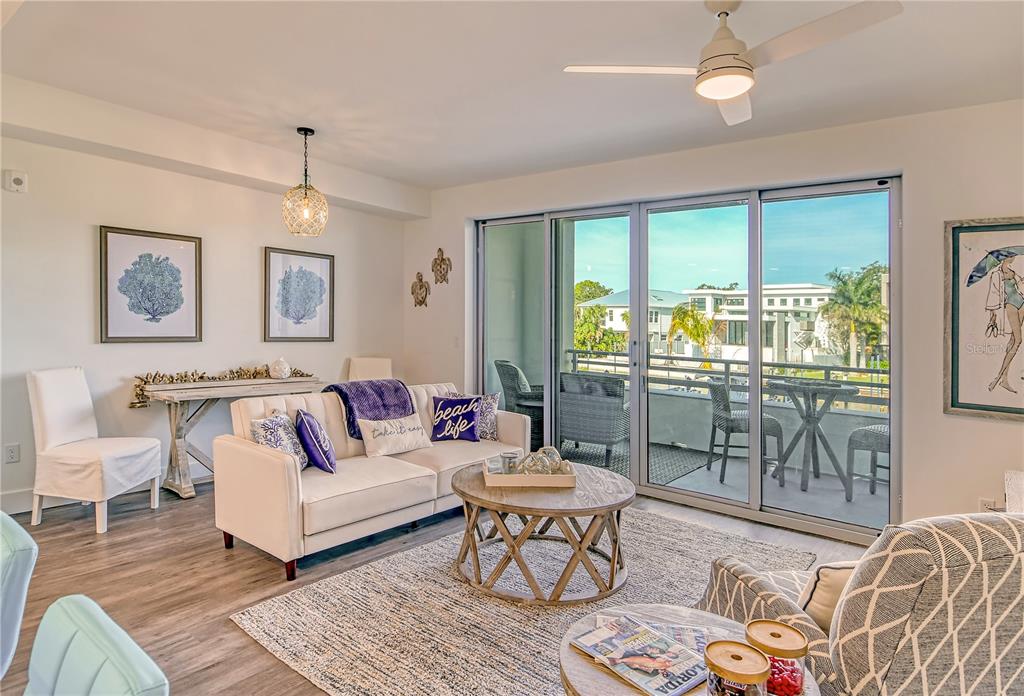 A living room features a sofa, coffee table, and sliding glass doors opening to a balcony — 1709 N TAMIAMI TRAIL UNIT 221, SARASOTA, FL