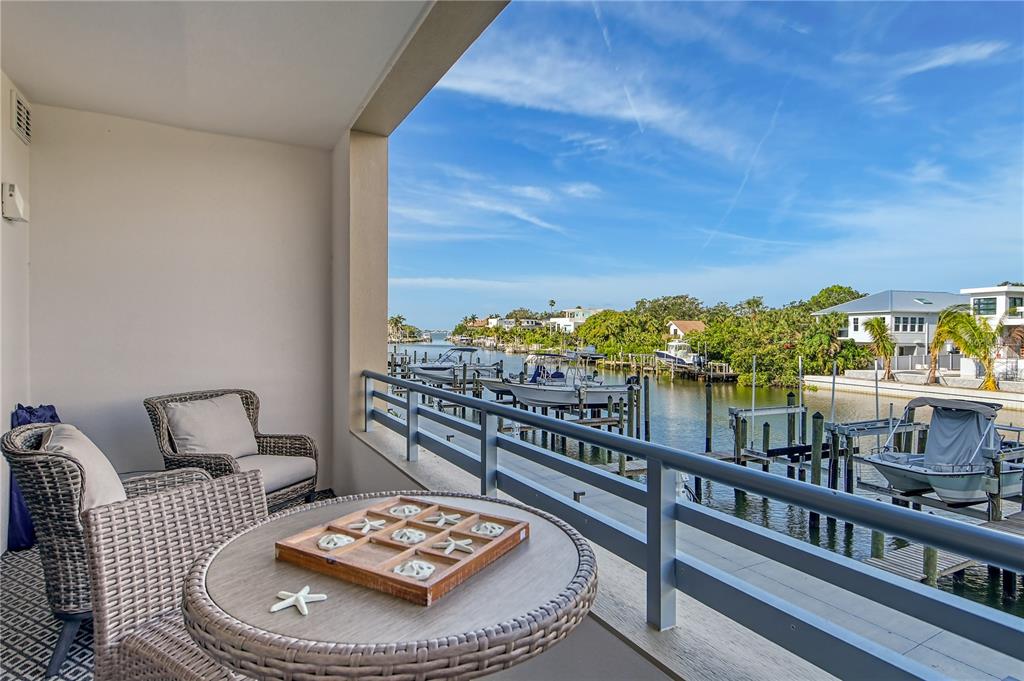 A balcony with wicker furniture overlooks a canal lined with boat docks and houses — 1709 N TAMIAMI TRAIL UNIT 221, SARASOTA, FL