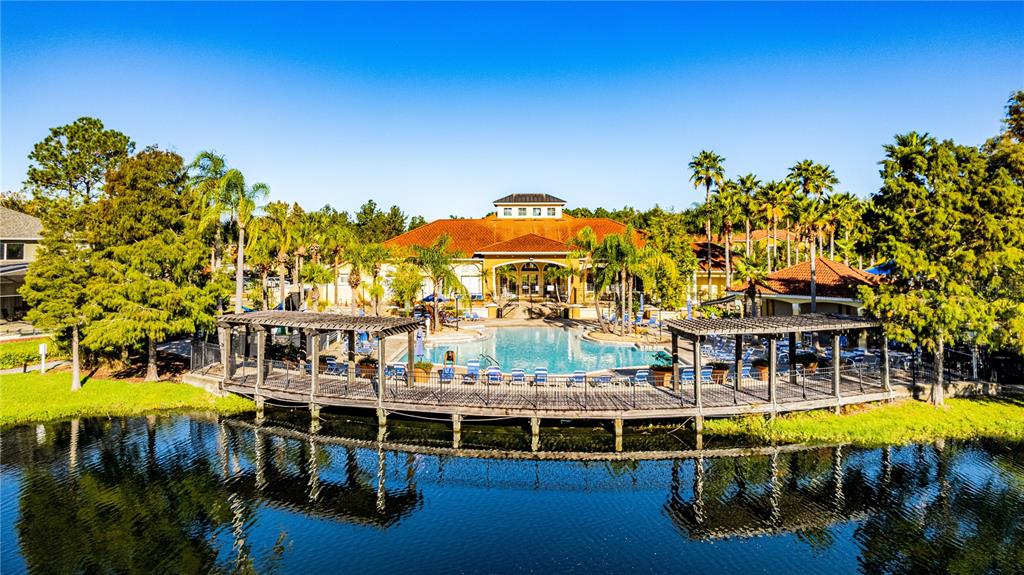 An outdoor swimming pool with a wooden deck sits in front of a clubhouse building — 4703 VERO BEACH PLACE, KISSIMMEE, FL