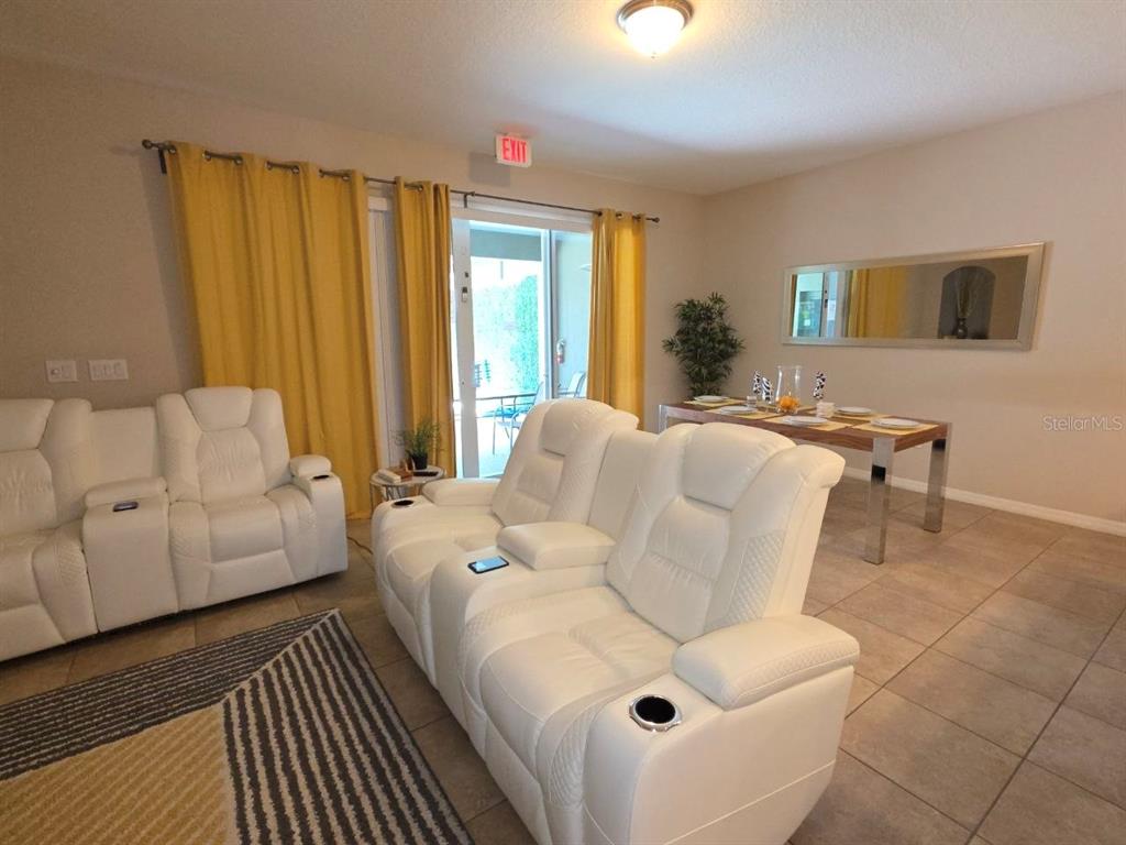 A living room features white reclining sofas, yellow curtains, and a dining area — 4746 TERRASONESTA DRIVE, DAVENPORT, FL