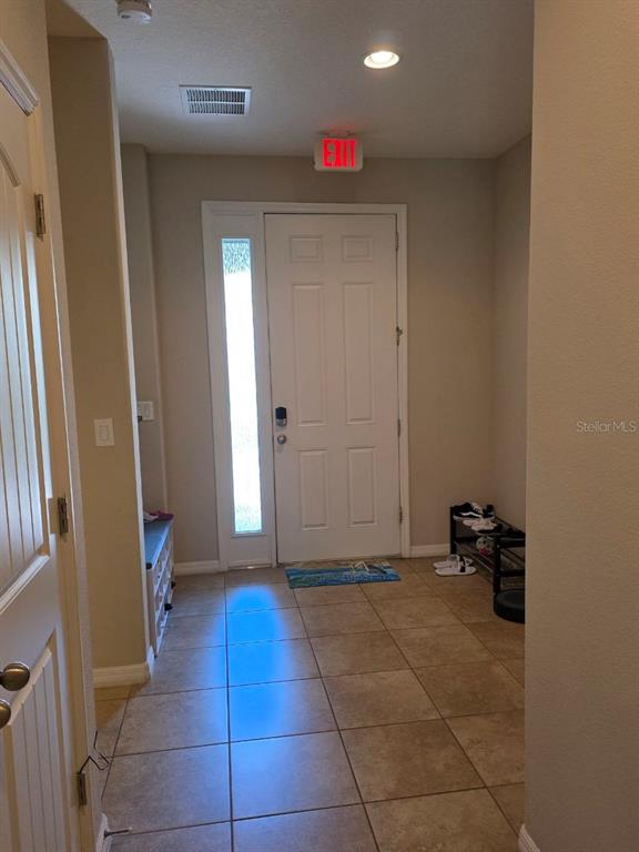 An entryway features a white front door with a sidelight, tile flooring, and an exit sign — 4746 TERRASONESTA DRIVE, DAVENPORT, FL
