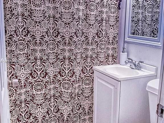 A bathroom features a patterned shower curtain, a white vanity with a sink, and a mirror — 5647 NW 5th Ct # B, Miami FL 33127, MIAMI, FL