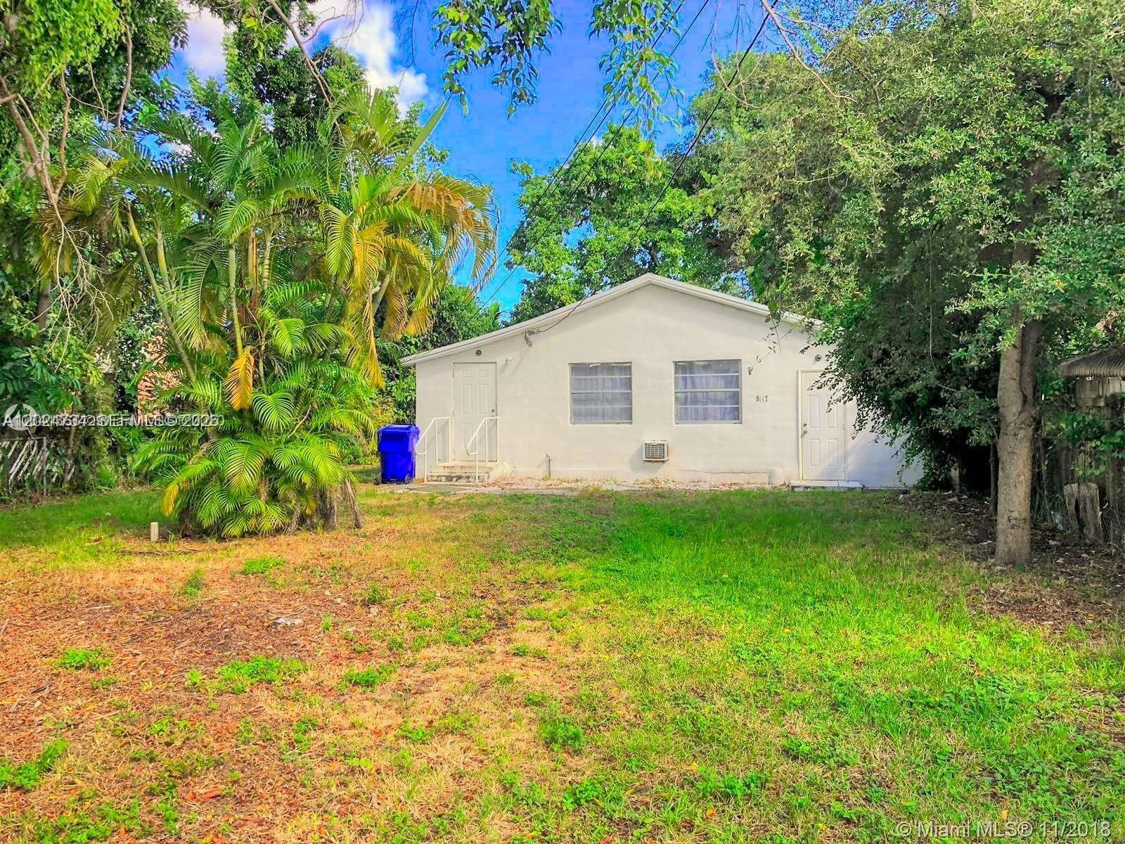 A white single-story house sits behind a grassy yard with a large palm tree — 5647 NW 5th Ct # B, Miami FL 33127, MIAMI, FL