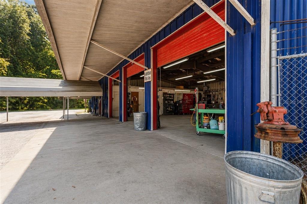 An open-air workshop features concrete flooring, blue metal siding, and several service bays — 16260 NW US HIGHWAY 441, ALACHUA, FL