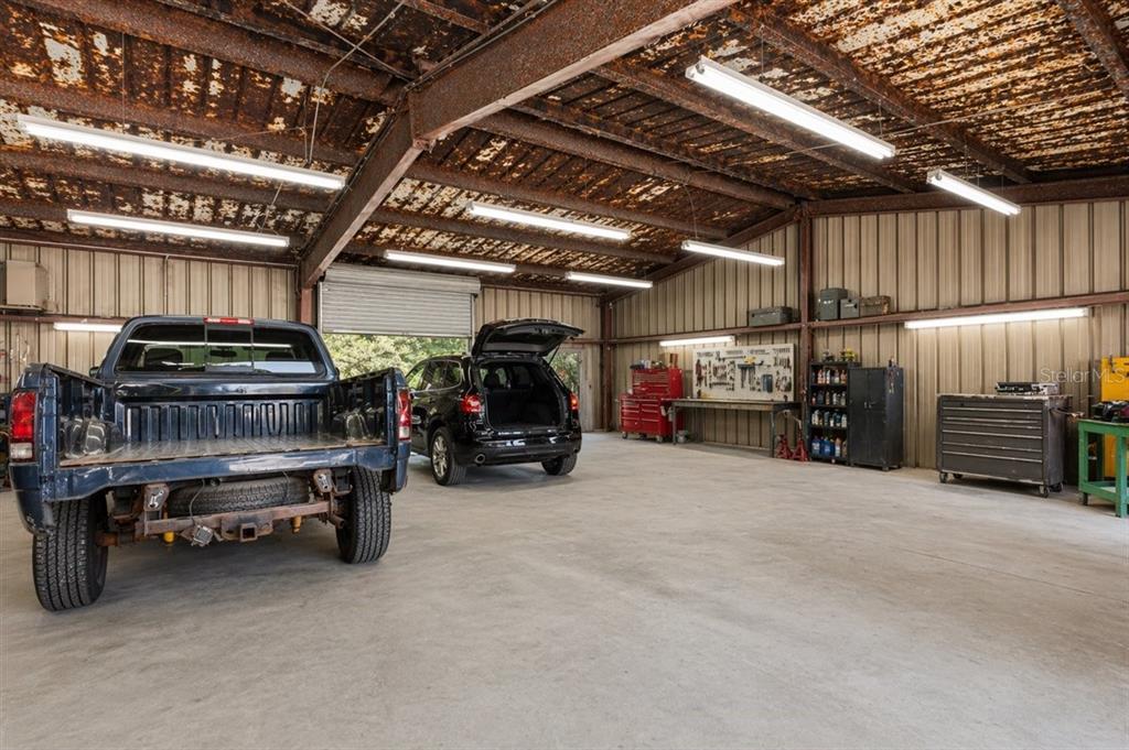 A spacious garage features a concrete floor, metal walls, and a rusted corrugated metal ceiling — 16260 NW US HIGHWAY 441, ALACHUA, FL