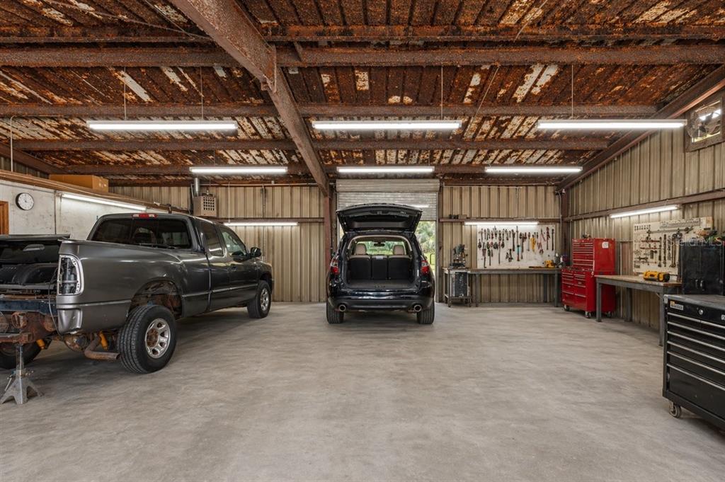 A spacious metal-walled garage features a concrete floor, overhead lighting, and two parked vehicles — 16260 NW US HIGHWAY 441, ALACHUA, FL