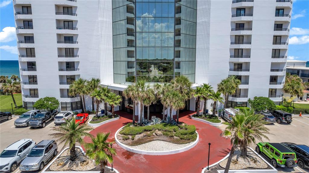 An exterior view of a multi-story white building with a circular driveway and palm trees — 2425 S ATLANTIC AVENUE UNIT 4060, DAYTONA BEACH, FL