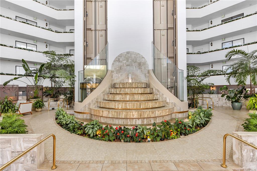 A tiered stone fountain sits in the center of a multi-story atrium with glass railings — 2425 S ATLANTIC AVENUE UNIT 4060, DAYTONA BEACH, FL