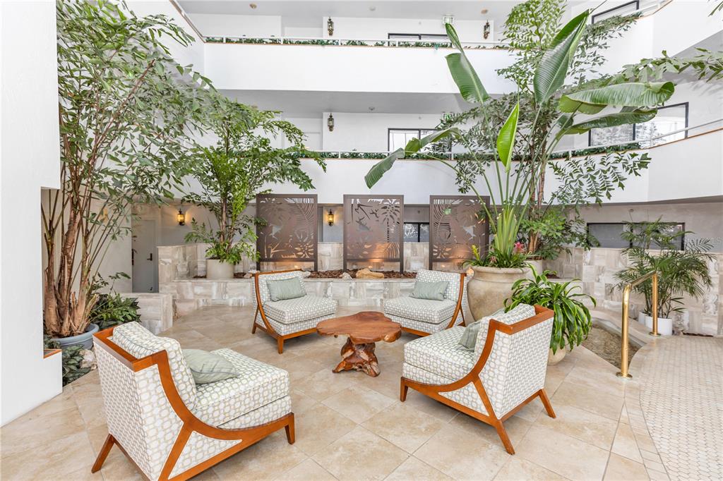 An indoor atrium features a seating area with four patterned armchairs and a wooden table — 2425 S ATLANTIC AVENUE UNIT 4060, DAYTONA BEACH, FL