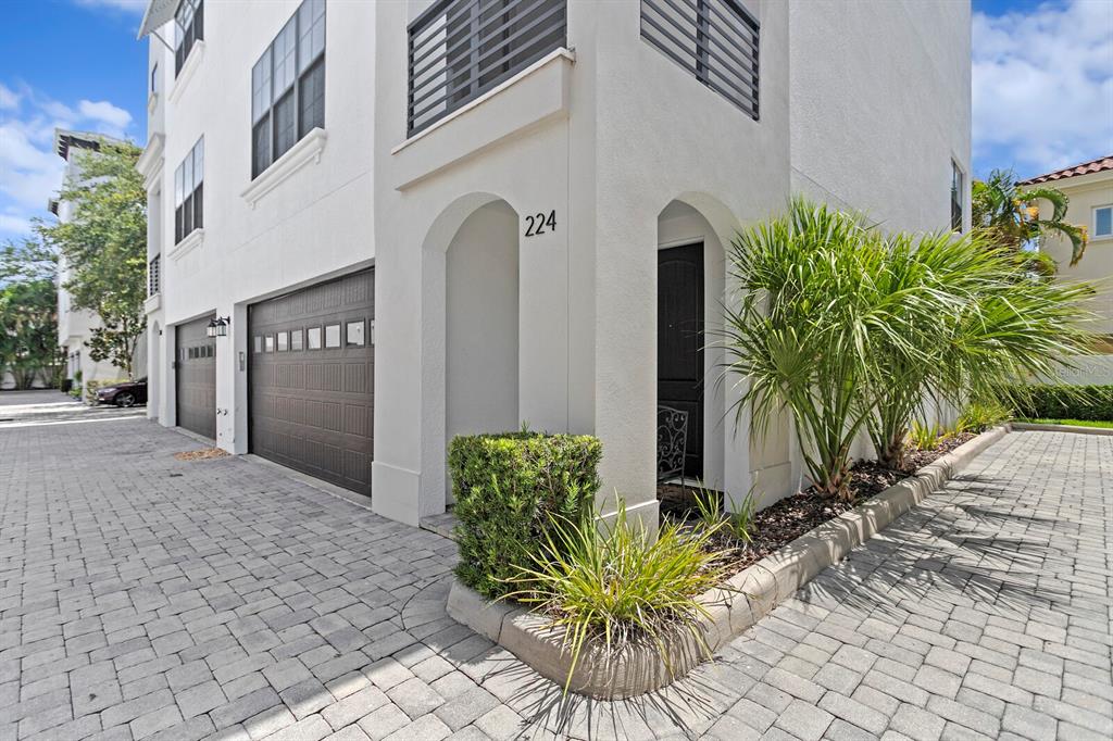 A multi-story white townhouse exterior features a garage, a front entrance, and paved driveway — 224 S AUDUBON AVENUE, TAMPA, FL