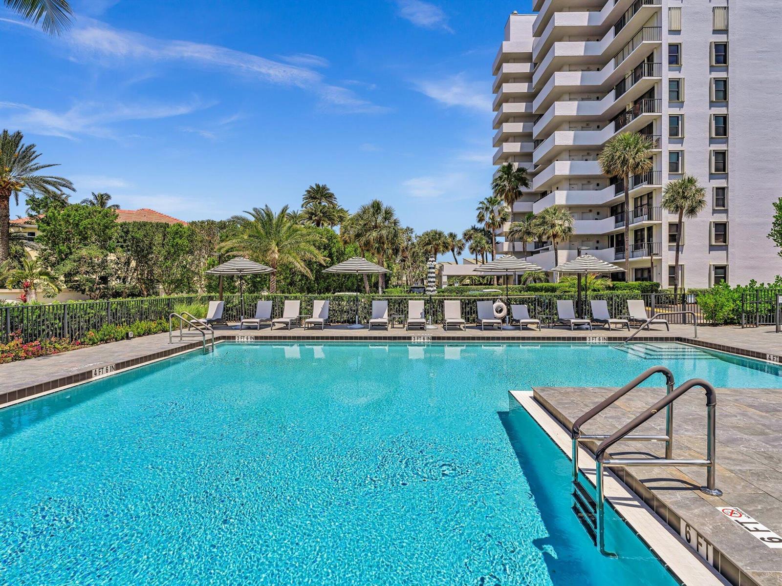 A swimming pool with lounge chairs and umbrellas sits in front of a tall building — 4600 S Ocean Boulevard # 502, Highland Beach FL 33487, HIGHLAND BEACH, FL