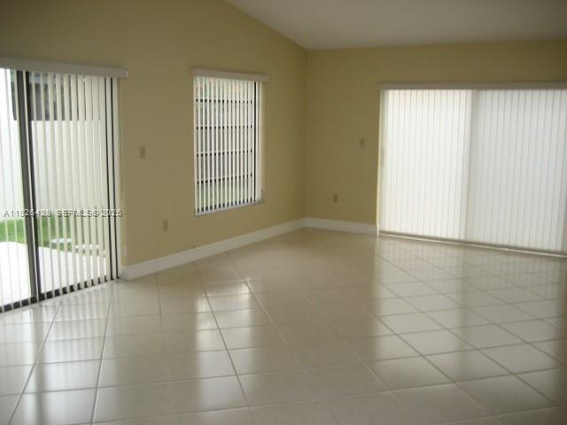 An empty room with light-colored tile flooring, beige walls, and vertical window blinds — 9044 SW 112 CT, Miami FL 33176, MIAMI, FL