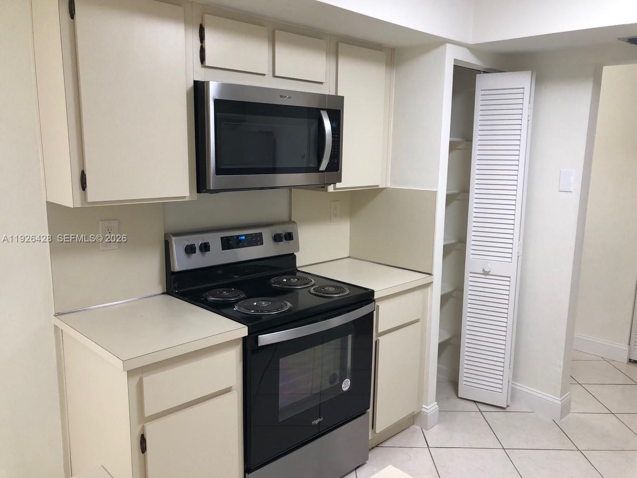 A kitchen features off-white cabinets, a black electric stove, a stainless microwave, and tile flooring — 9044 SW 112 CT, Miami FL 33176, MIAMI, FL