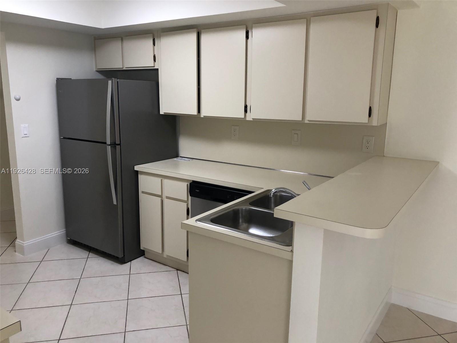 A kitchen features off-white cabinets, a grey refrigerator, a double sink, and tiled flooring — 9044 SW 112 CT, Miami FL 33176, MIAMI, FL