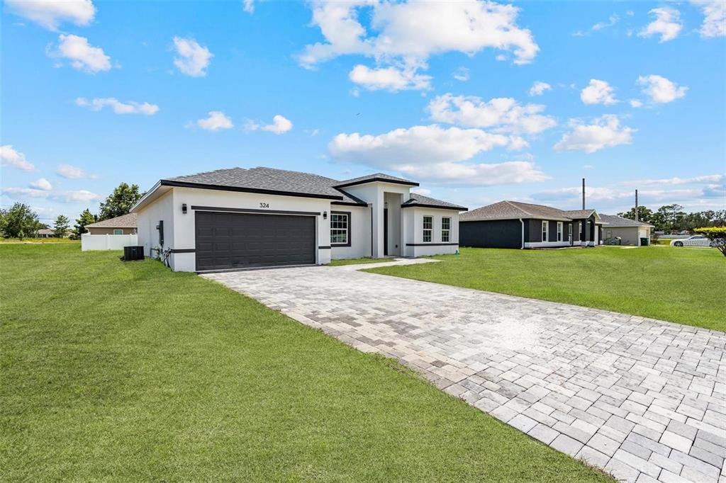 A single-story house with a paved driveway, dark garage door, and light-colored exterior walls — 324 MARION OAKS TRAIL, OCALA, FL