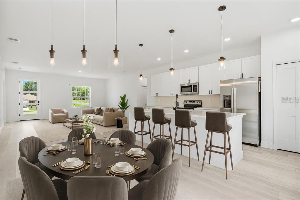 An open-concept kitchen and dining area features white cabinetry, a kitchen island, and pendant lighting — 324 MARION OAKS TRAIL, OCALA, FL