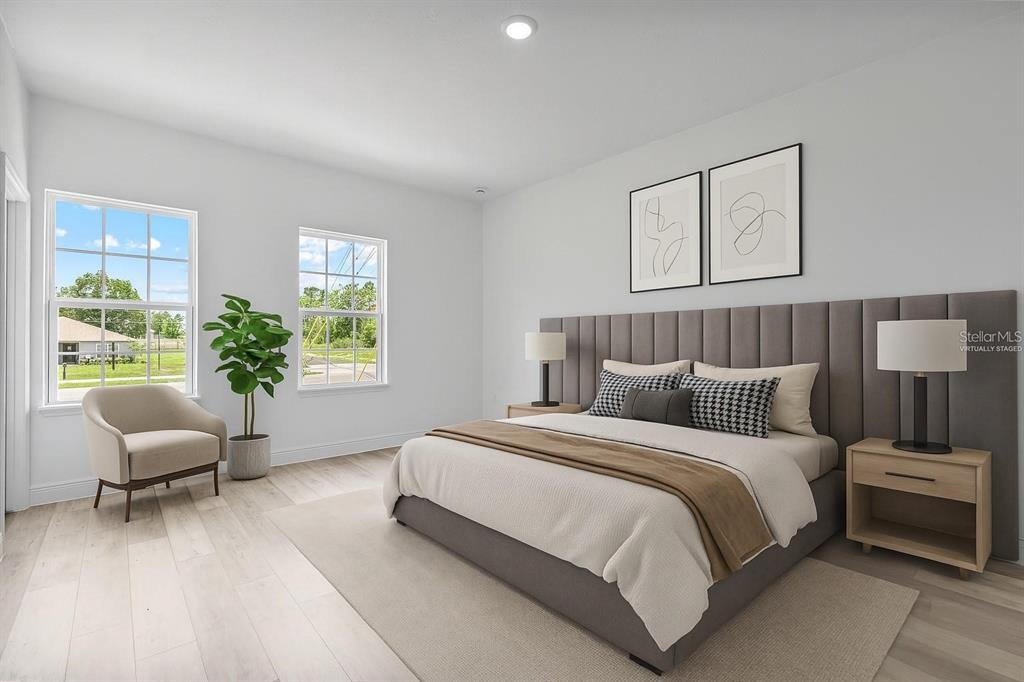 This virtually staged bedroom features light wood flooring, a gray upholstered headboard, and two windows — 324 MARION OAKS TRAIL, OCALA, FL