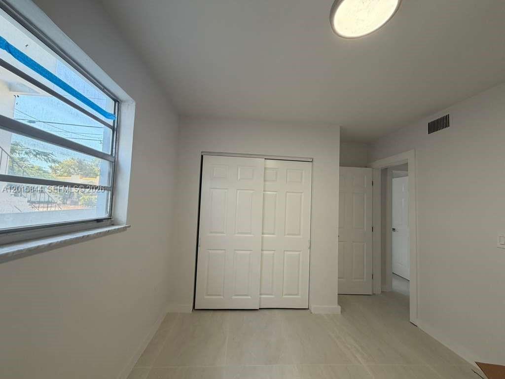 A bedroom features light-colored tile flooring, white walls, a sliding closet, and a window — 1461 SW 7th St # 1, Miami FL 33135, MIAMI, FL