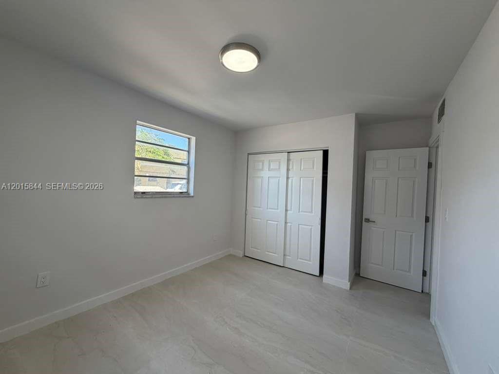 A bedroom features light-colored flooring, white walls, a window, a closet, and a door — 1461 SW 7th St # 1, Miami FL 33135, MIAMI, FL