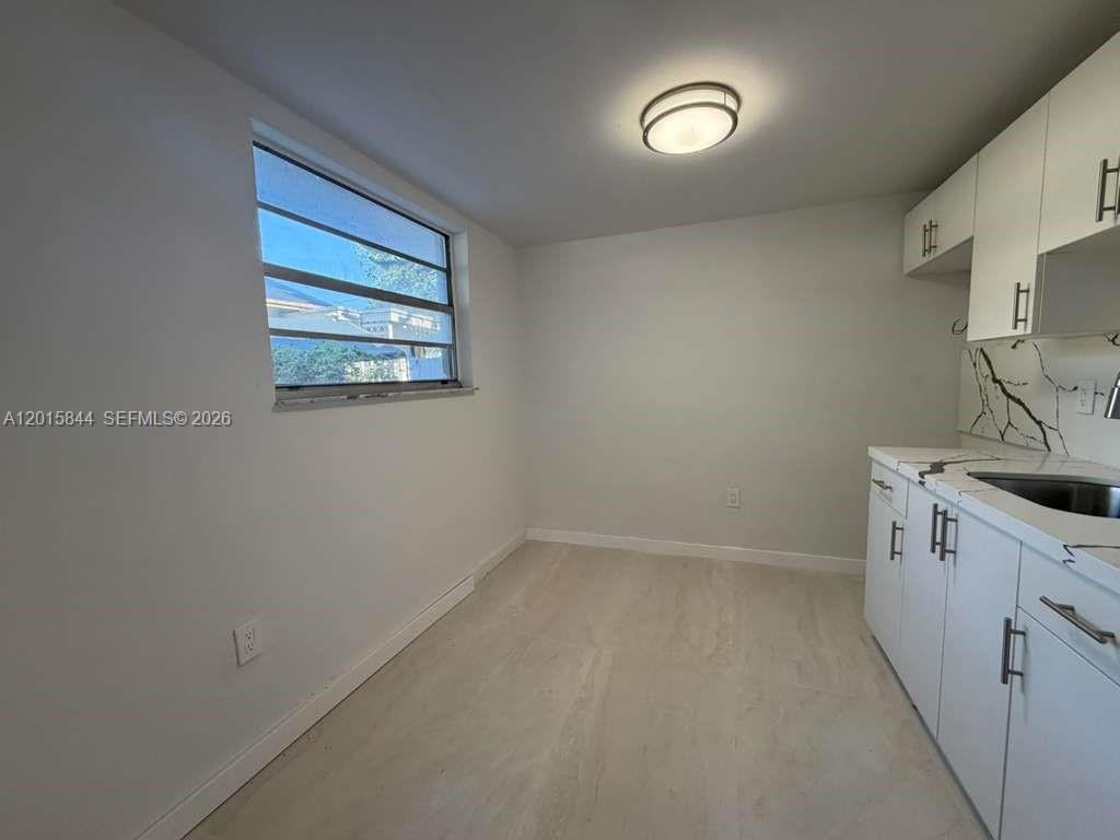 A small kitchen features white cabinets, a marble-patterned backsplash, and a window — 1461 SW 7th St # 1, Miami FL 33135, MIAMI, FL