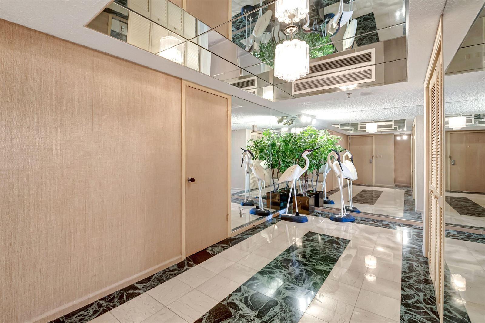 A mirrored foyer features a marble floor with green accents, a chandelier, and crane statues — 3407 S Ocean Boulevard # 4d, Highland Beach FL 33487, HIGHLAND BEACH, FL