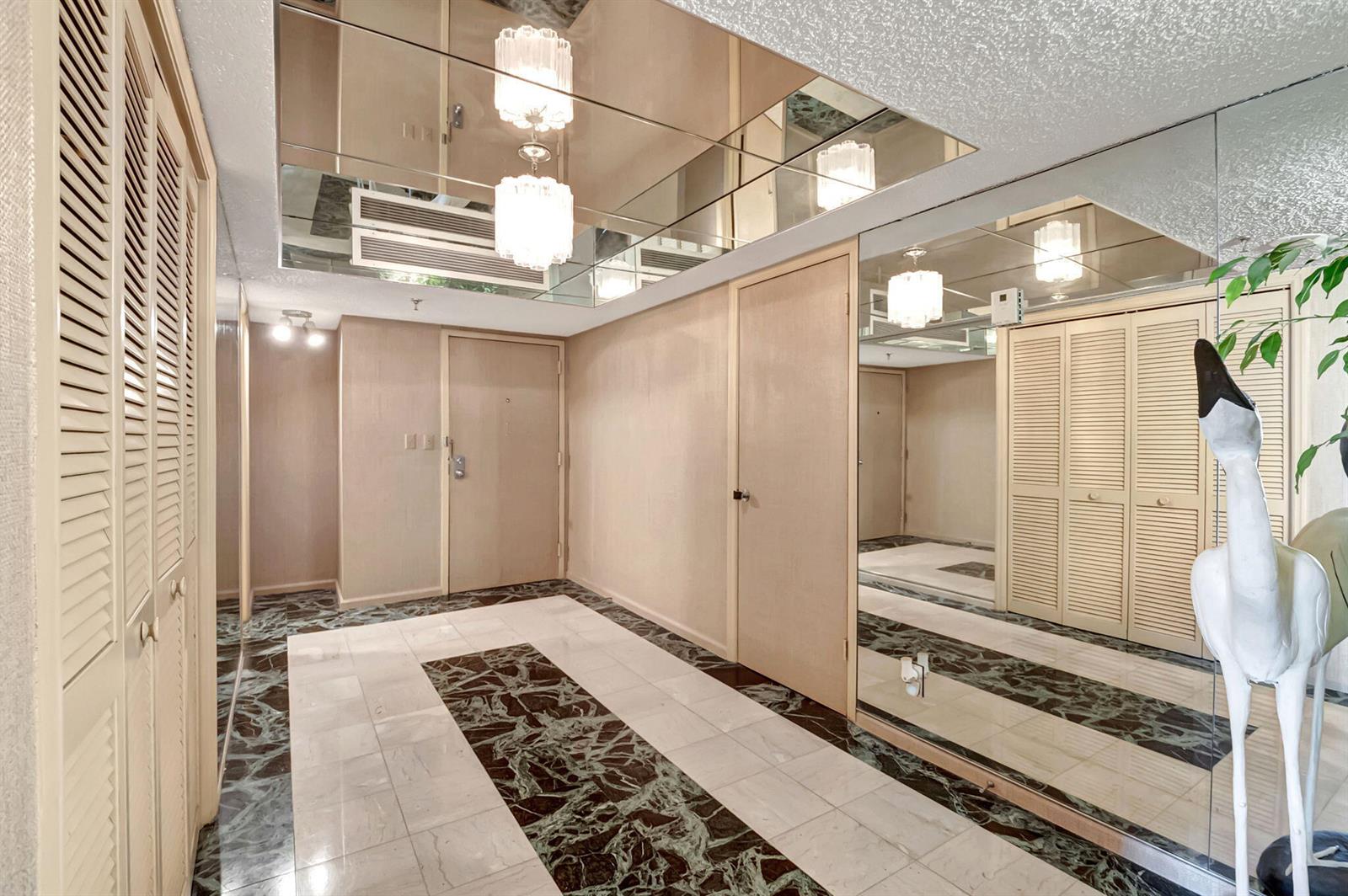 An entryway features a mirrored ceiling, marble-patterned tile flooring, and louvered closet doors — 3407 S Ocean Boulevard # 4d, Highland Beach FL 33487, HIGHLAND BEACH, FL