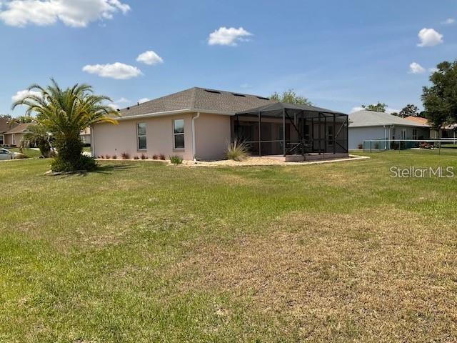 A single-story house with a screened-in lanai sits on a large, grassy lot — 4921 NW 33RD LANE, OCALA, FL
