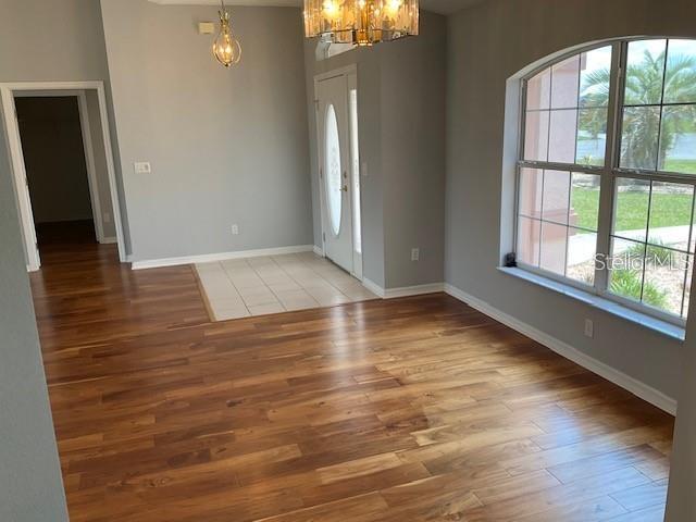 An interior view of a room with wood flooring, a tiled entryway, and a large window — 4921 NW 33RD LANE, OCALA, FL