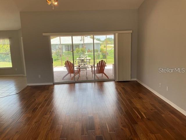 A living room with wood flooring features a large sliding glass door opening to a patio — 4921 NW 33RD LANE, OCALA, FL