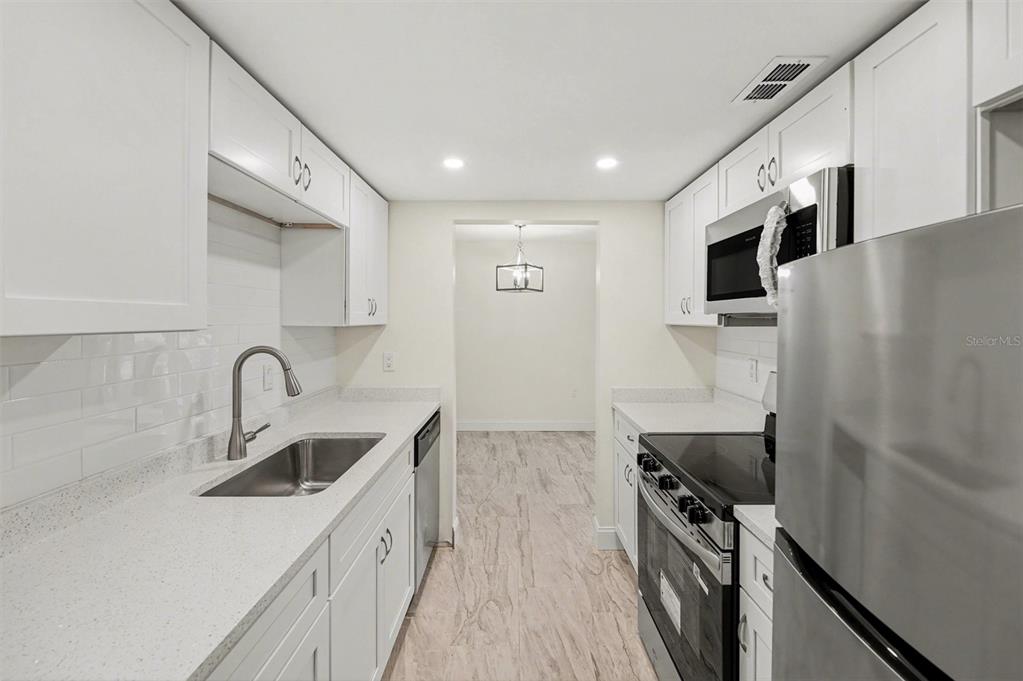A galley kitchen features white cabinets, stainless steel appliances, and light-colored countertops — 11409 8TH STREET N UNIT 1507, ST PETERSBURG, FL