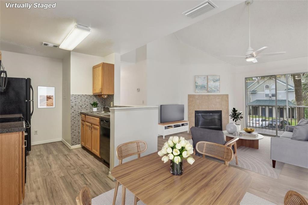 An open-concept kitchen, dining area, and living room with a fireplace and sliding glass doors — 6088 WESTGATE DRIVE UNIT 201, ORLANDO, FL