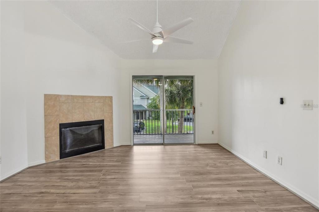 An empty living room features a fireplace, light wood-look flooring, and a sliding glass door — 6088 WESTGATE DRIVE UNIT 201, ORLANDO, FL