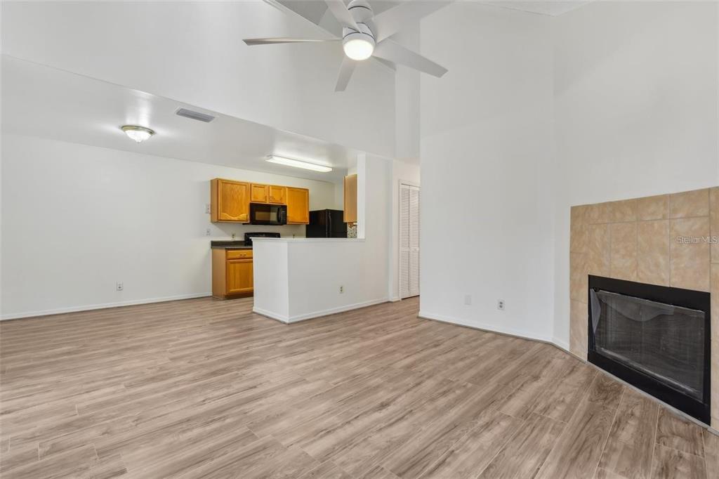 A living room with a fireplace and wood-look flooring opens to a kitchen with cabinets — 6088 WESTGATE DRIVE UNIT 201, ORLANDO, FL