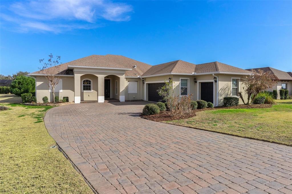 A single-story house with a paved driveway, two garage doors, and a covered entryway — 39634 GROVE HEIGHTS, LADY LAKE, FL