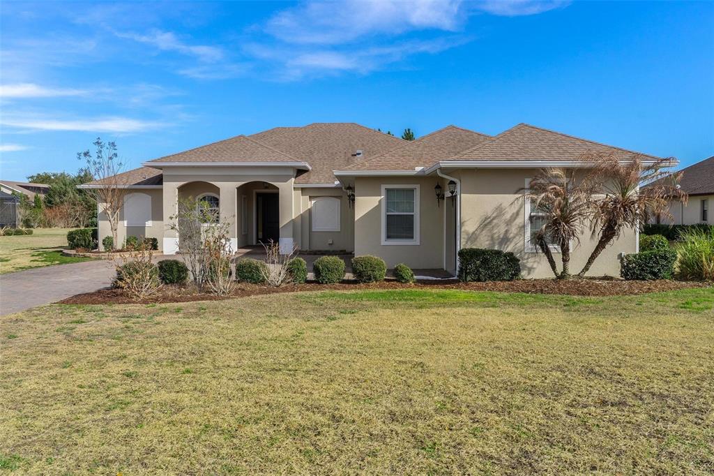 A single-story tan stucco house with a hip roof and a paved driveway — 39634 GROVE HEIGHTS, LADY LAKE, FL