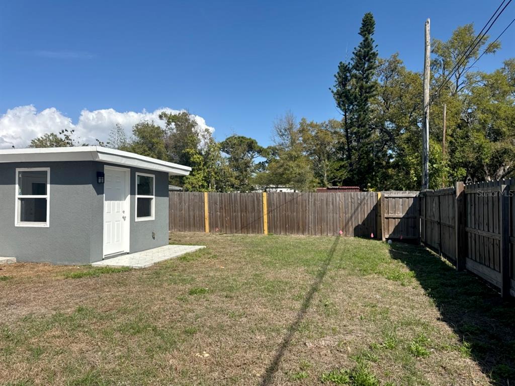 A gray shed with a white door stands in a fenced backyard under a blue sky — 5520 20TH AVENUE S, GULFPORT, FL