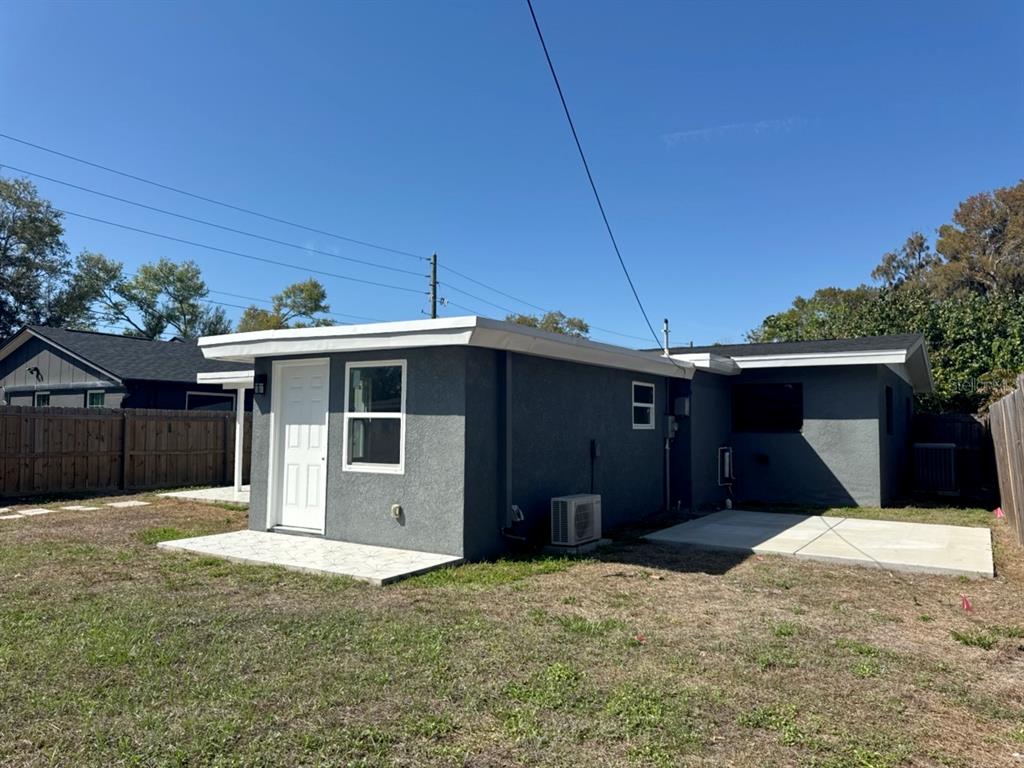 A gray stucco exterior of a small house with a white door and concrete patio — 5520 20TH AVENUE S, GULFPORT, FL