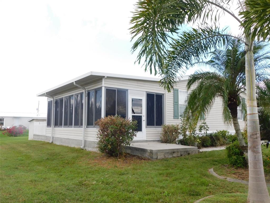 A light-colored mobile home features a screened-in porch and a concrete patio under a palm tree — 11739 SW LEMON AVENUE, ARCADIA, FL