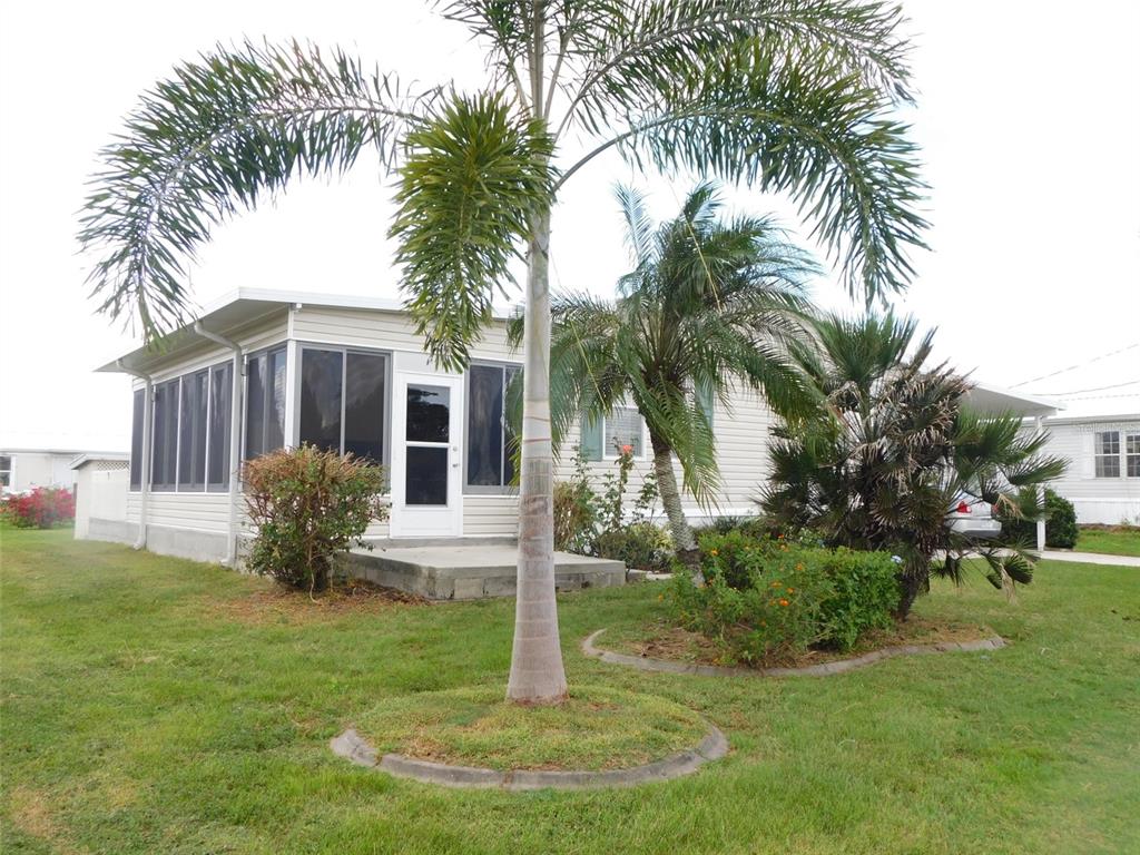 A single-story manufactured home features a screened-in porch, a palm tree, and a concrete patio — 11739 SW LEMON AVENUE, ARCADIA, FL