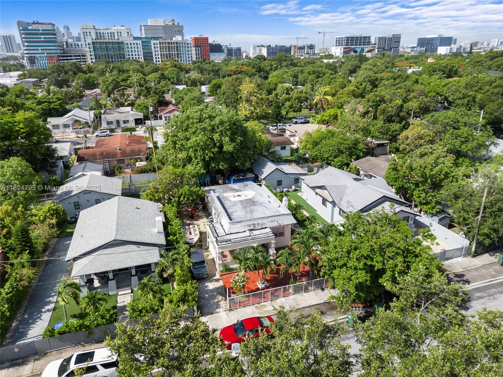An aerial view shows several single-story houses surrounded by lush trees and city buildings — 50 NW 34th Ter, Miami FL 33127, MIAMI, FL