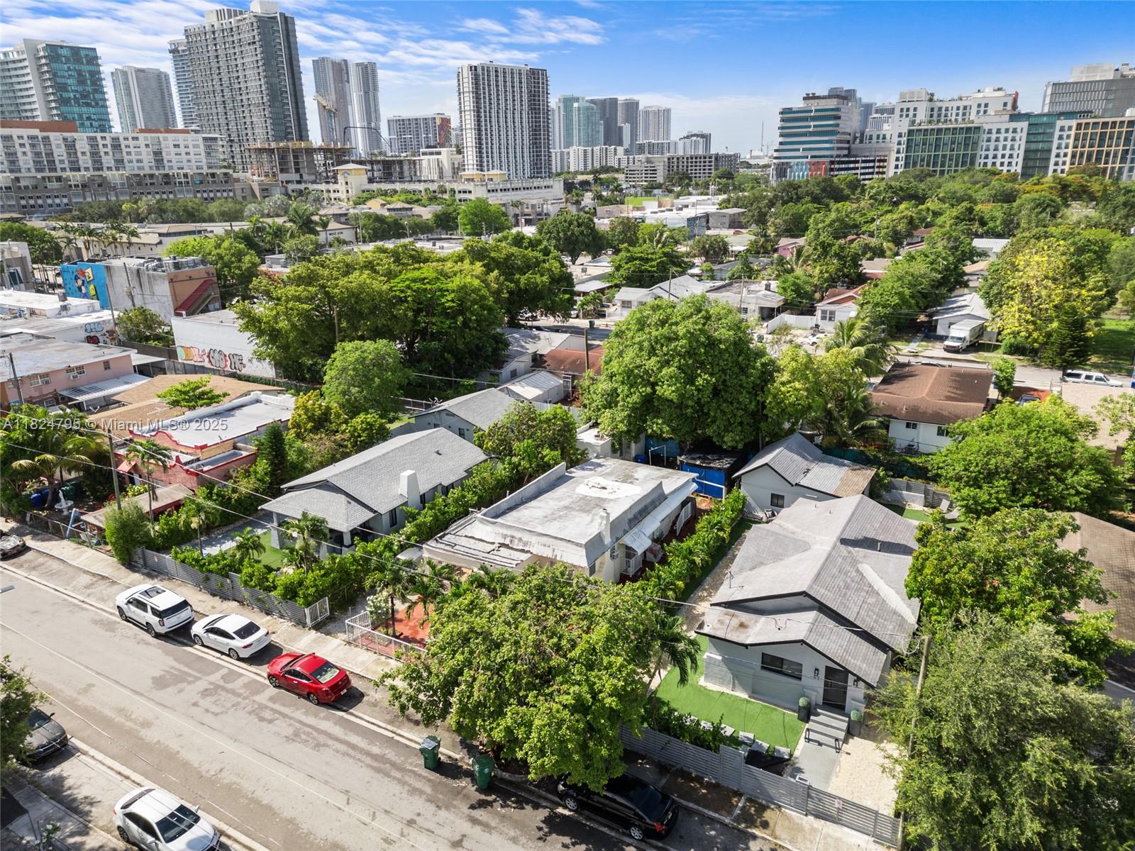 An aerial view shows several single-story residential houses along a street with city skyscrapers behind — 50 NW 34th Ter, Miami FL 33127, MIAMI, FL
