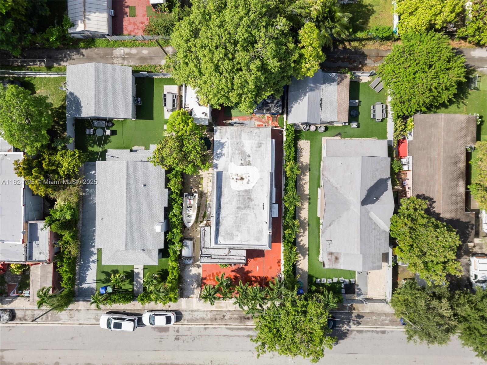 Aerial view of three residential properties with gray roofs, green lawns, and parked vehicles — 50 NW 34th Ter, Miami FL 33127, MIAMI, FL
