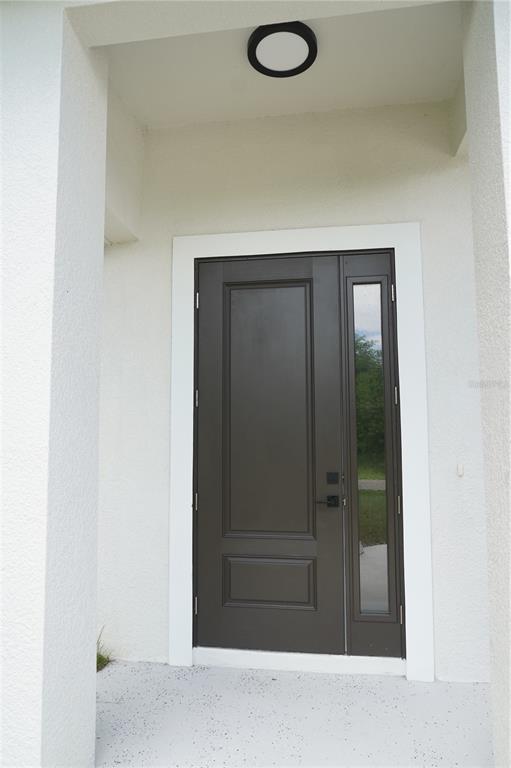 A dark brown front door with a side window is set within a white entryway — 5820 BRICKELL DRIVE, NORTH PORT, FL