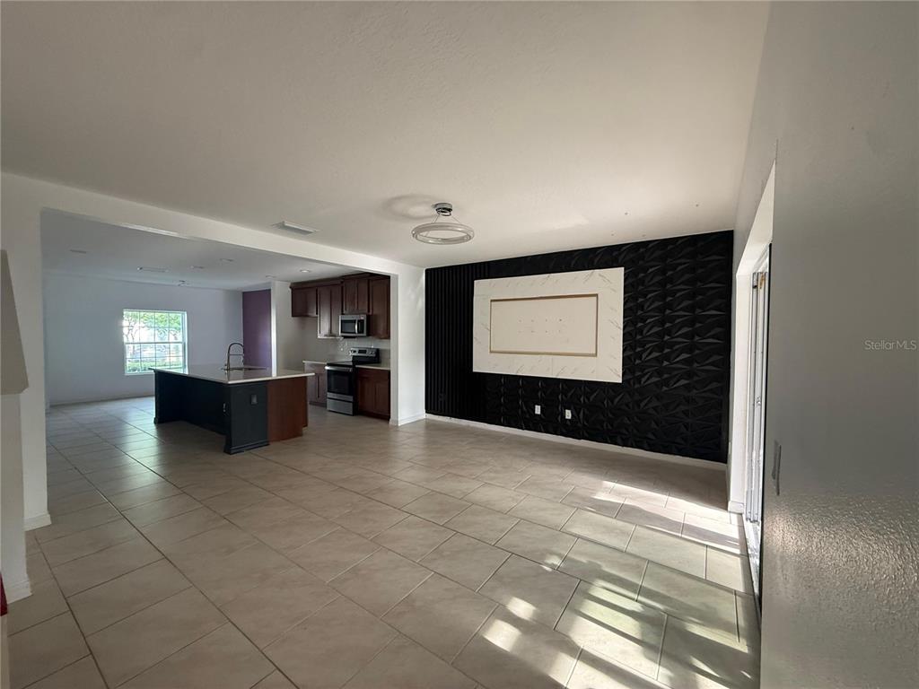 An open-concept living area features a black textured accent wall and a kitchen with island — 1182 SAND TORCH CIRCLE, DAVENPORT, FL