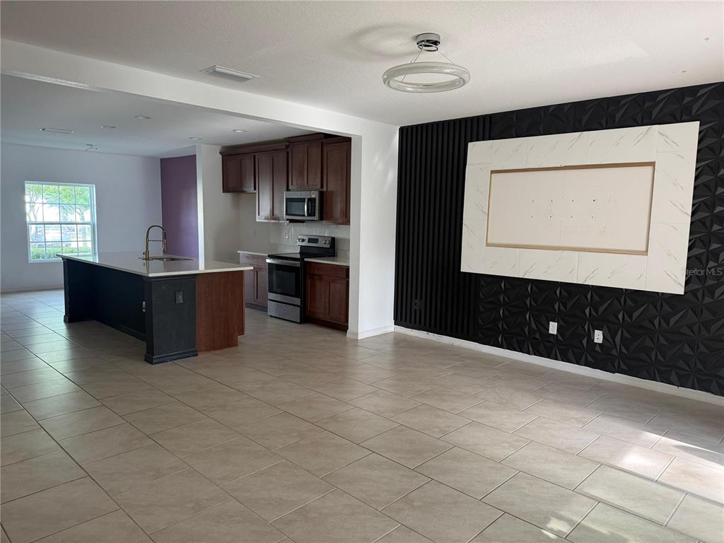 An open-concept living area features a kitchen with dark wood cabinets and a tiled floor — 1182 SAND TORCH CIRCLE, DAVENPORT, FL